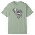 A sage green short-sleeve crewneck t-shirt featuring a black and white floral South Carolina graphic on the chest, displayed flat against a solid white background.
