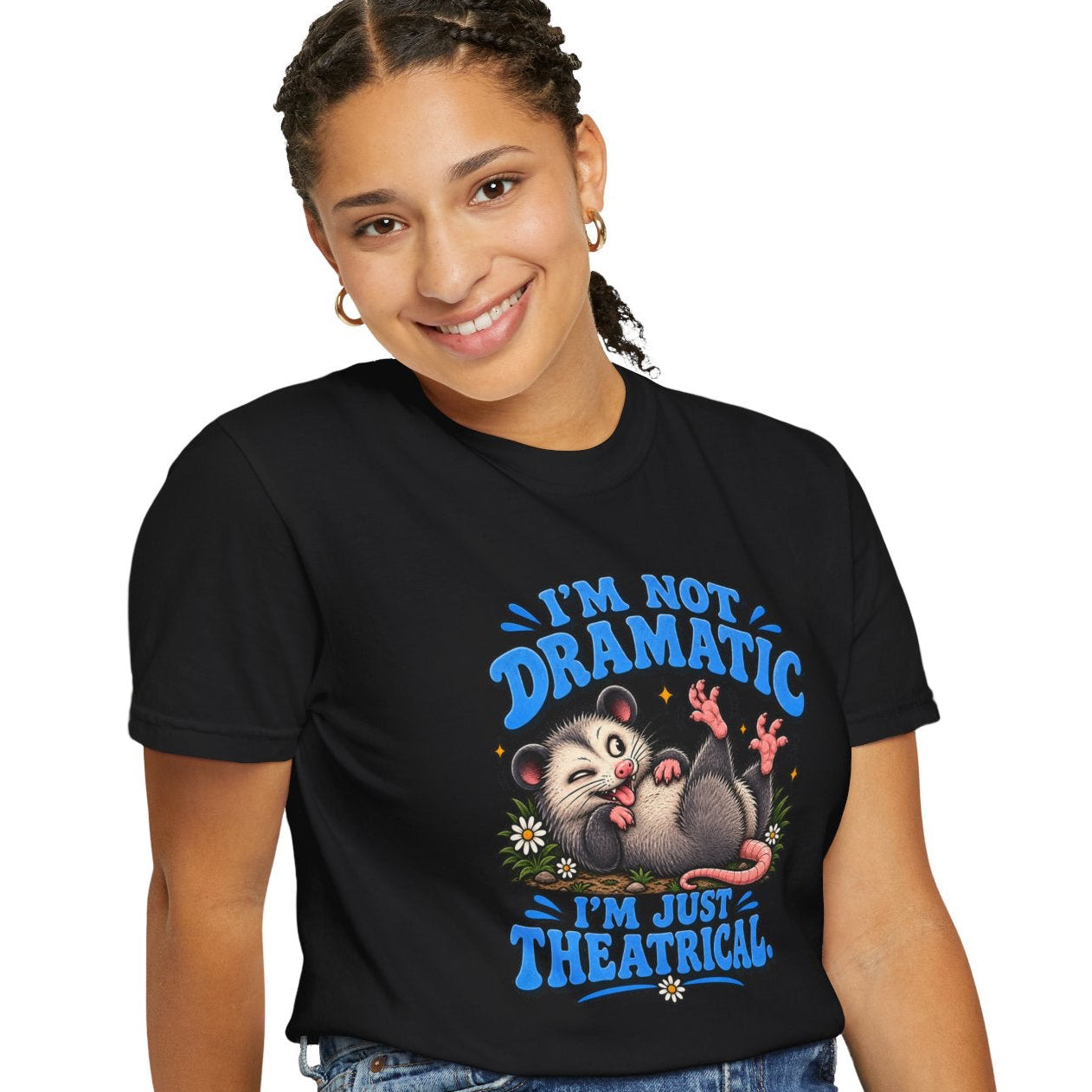 A woman wearing a black graphic t-shirt with a blue and white design, paired with blue jeans, sitting on a stool against a white background.