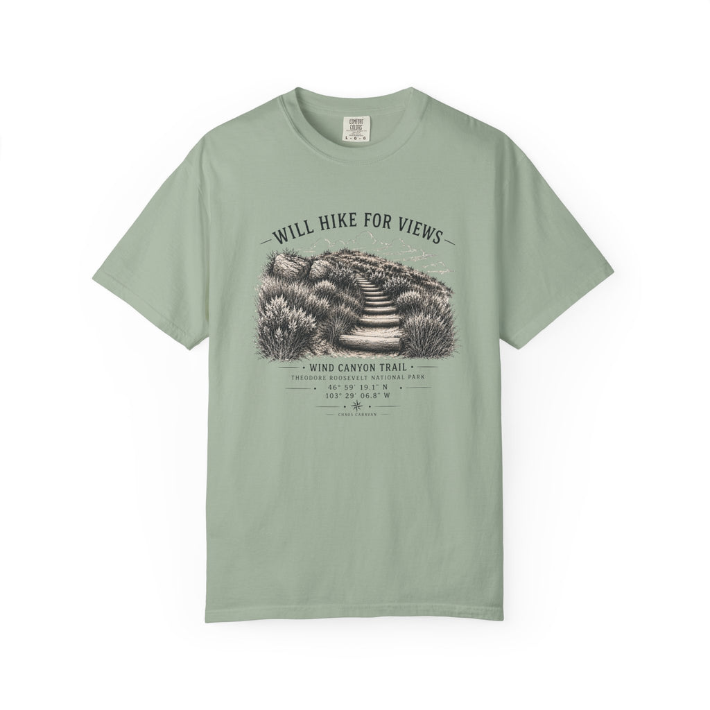 A sage green short-sleeve t-shirt with a vintage-style black and white graphic of a hiking trail and the text 'WILL HIKE FOR VIEWS' and 'WIND CANYON TRAIL'.
