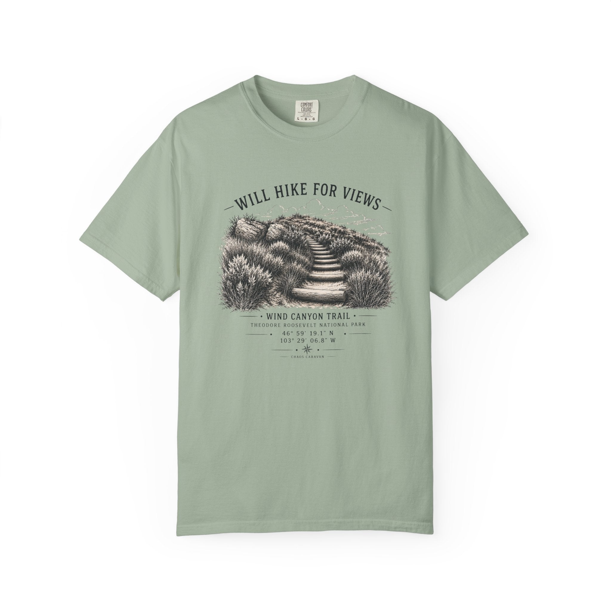 A sage green short-sleeve t-shirt with a vintage-style black and white graphic of a hiking trail and the text 'WILL HIKE FOR VIEWS' and 'WIND CANYON TRAIL'.