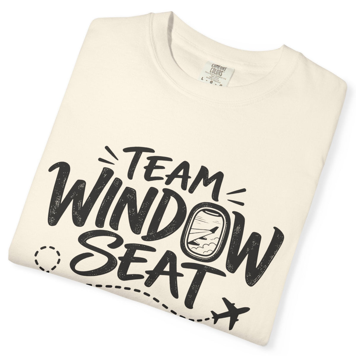 A folded cream-colored crewneck t-shirt with a black graphic print that reads 'TEAM WINDOW SEAT' with an airplane window illustration, shown on a plain white background.
