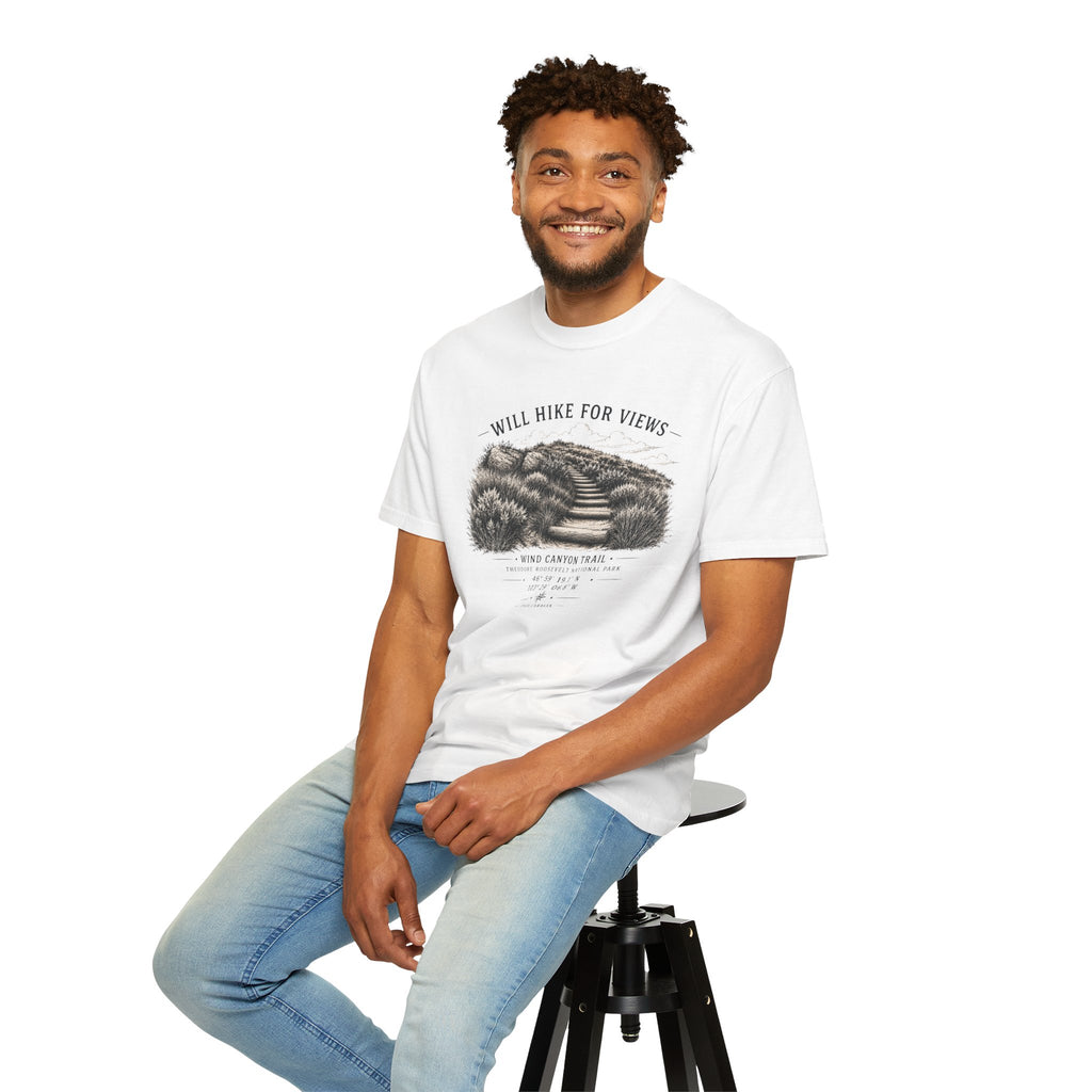 Man sitting on a stool wearing a white t-shirt with a graphic design and text.