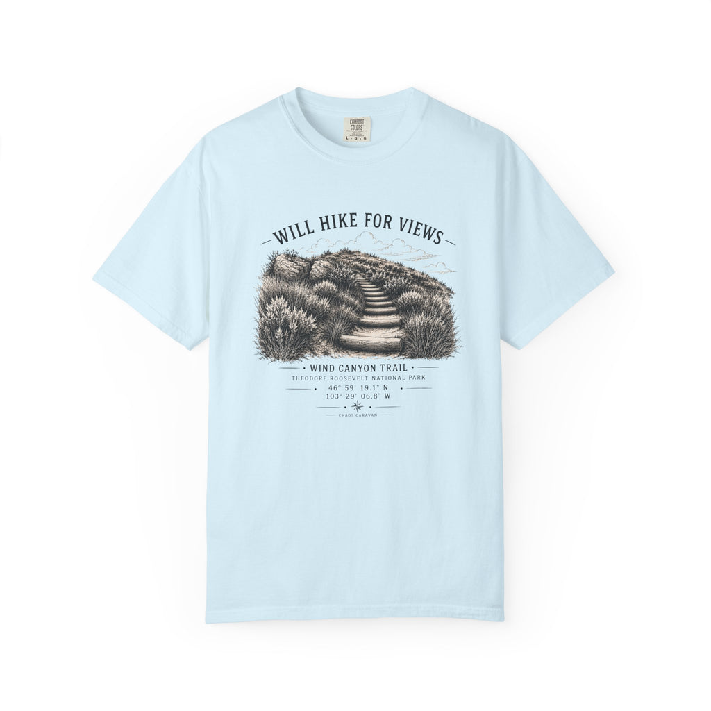 A light blue short-sleeve crewneck t-shirt featuring a black and white graphic print of a hiking trail in a desert landscape with the text 'WILL HIKE FOR VIEWS' and 'WIND CANYON TRAIL'.