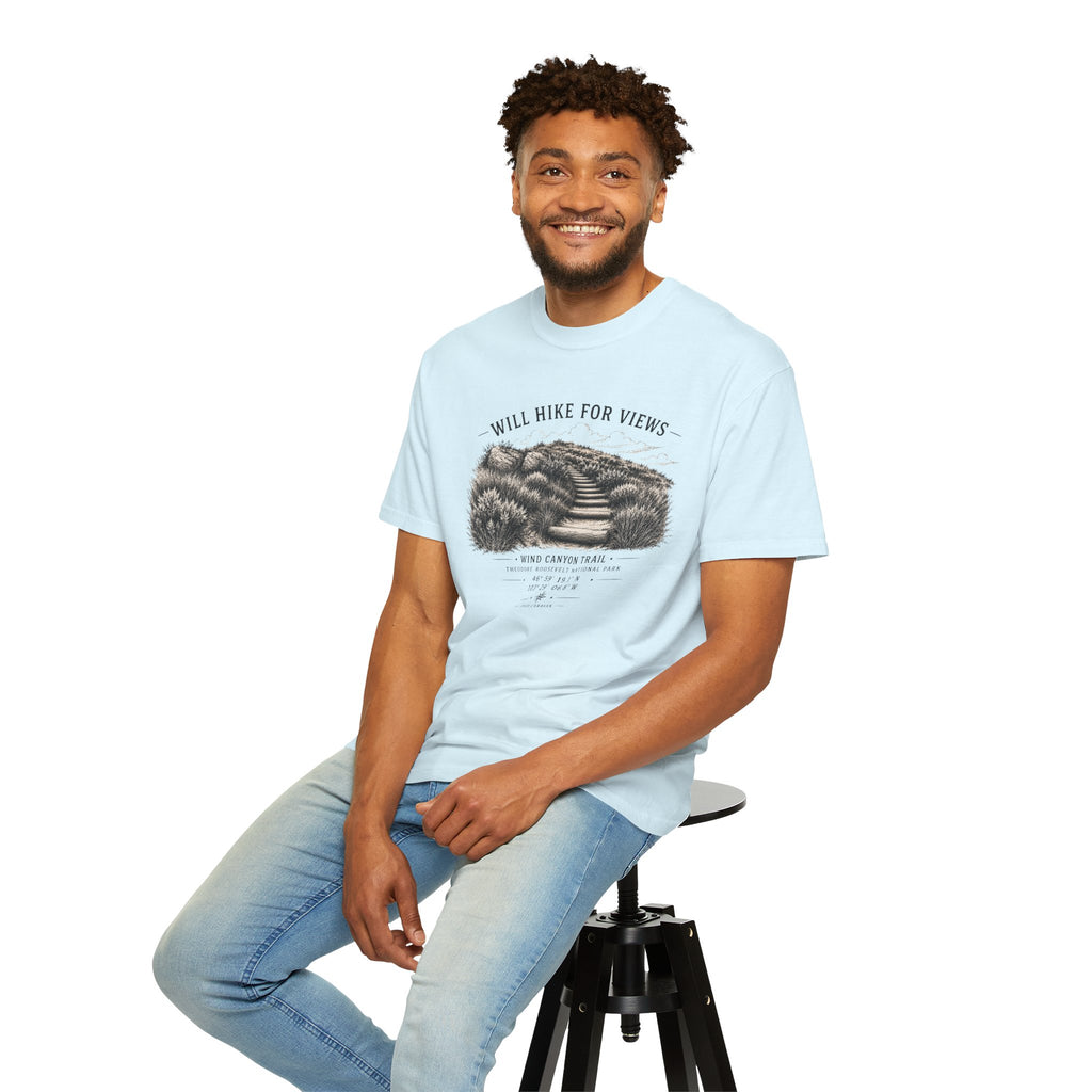 Man sitting on a stool wearing a light blue t-shirt with a graphic design.