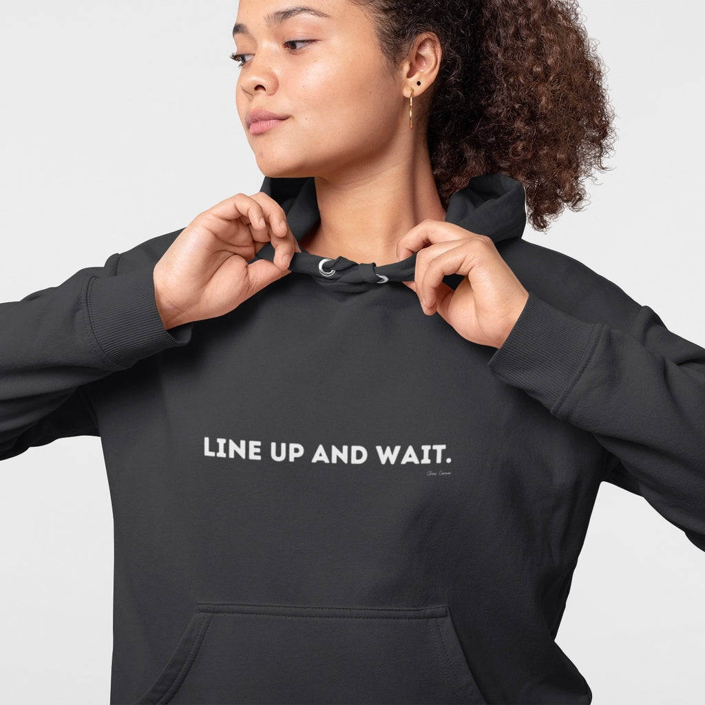 Person wearing a black hoodie with 'LINE UP AND WAIT.' text on a black background
