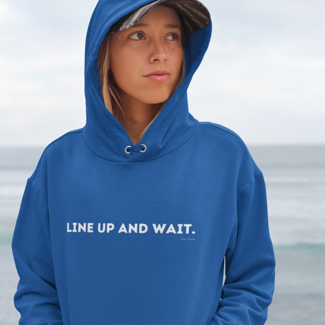 Person wearing a blue hoodie with 'LINE UP AND WAIT.' text against a blurred background